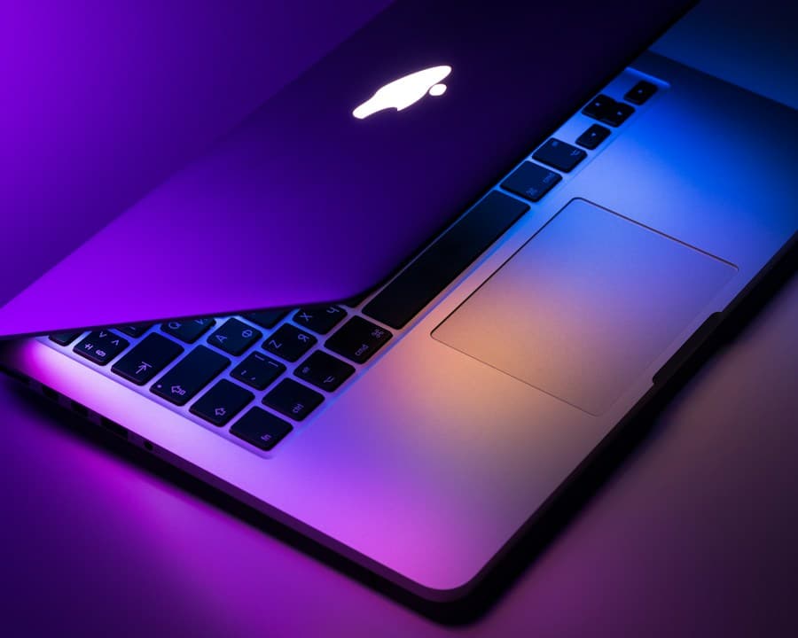 Detailansicht eines geöffneten Apple MacBook mit beleuchteter Tastatur und Trackpad